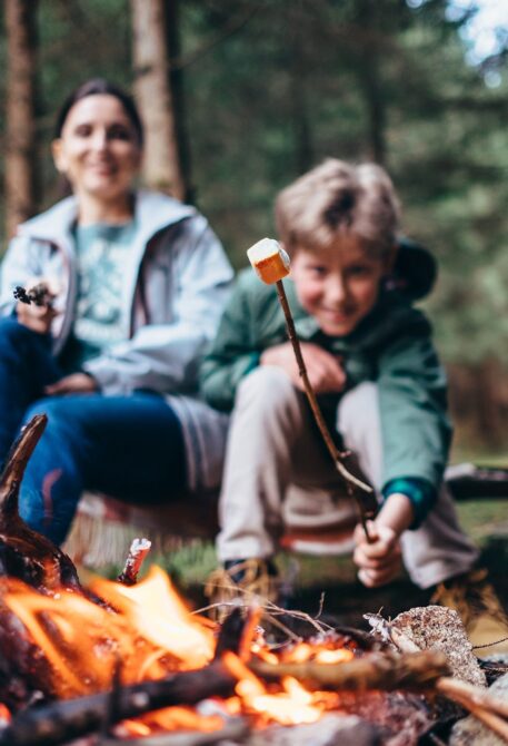 A parent and child roasting marshmallows over a campfire