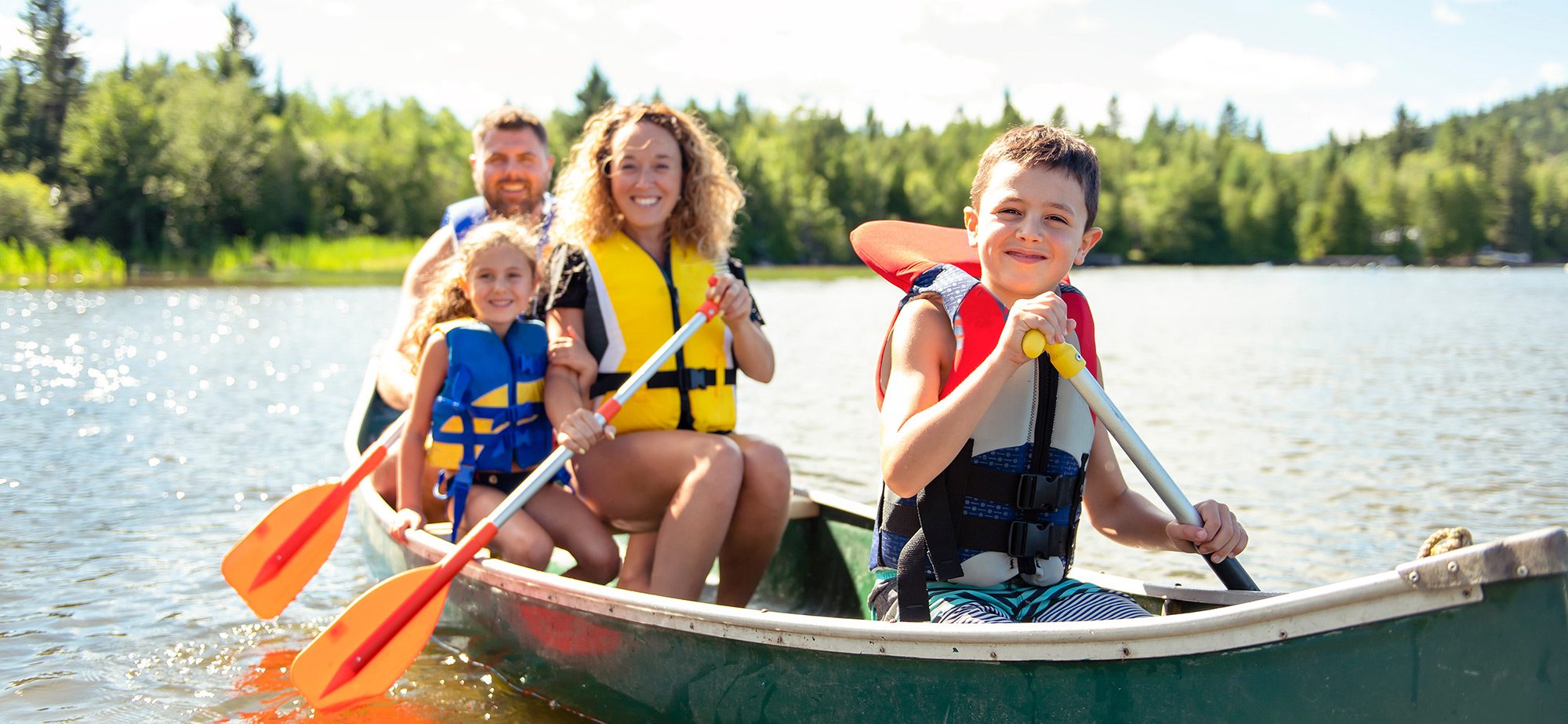 A family of four paddling a canoe on the camp lake
