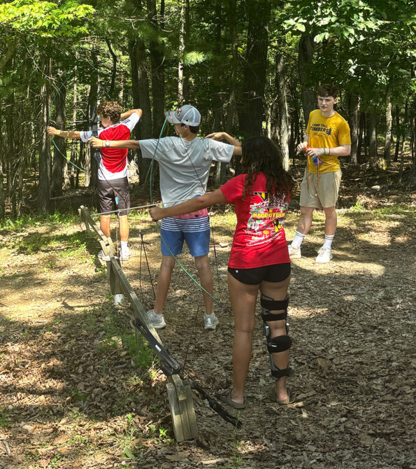 Campers and a counselor working together on the low ropes challenge course.